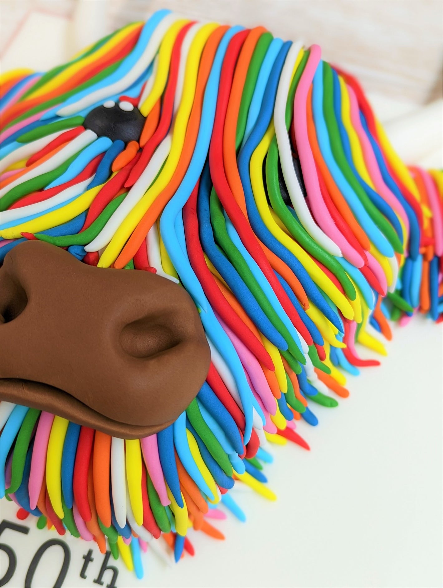 A Highland Cow Cake with Multicoloured Hair based on Steven Brown's McCoo Cow portraits